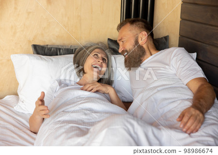 Mature couple staying in bed and looking happy 98986674