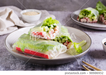 Vegetarian spring rolls with cucumber, crab sticks and lettuce on a plate on the table. Vegetarian spring rolls with cucumber, crab sticks and lettuce on a plate on the table. 98986932