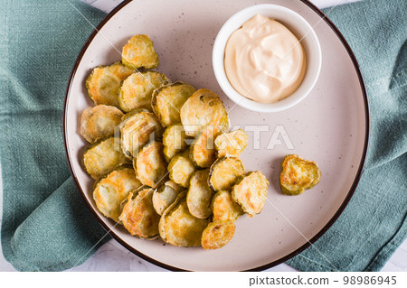 Fried pickles and sauce on a plate. American snack. Top view. Closeup Fried pickles and sauce on a plate. American snack. Top view. Closeup 98986945