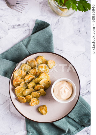 Fried pickles appetizer and sauce in a bowl on a plate. Homemade snack. Top and vertical view Fried pickles appetizer and sauce in a bowl on a plate. Homemade snack. Top and vertical view 98986946