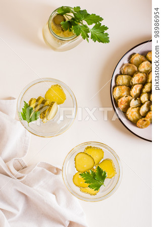 Cold pickleback cocktail with pickles and parsley in glasses on the table. Top and vertical view Cold pickleback cocktail with pickles and parsley in glasses on the table. Top and vertical view 98986954
