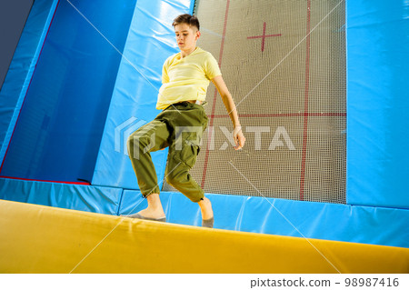 Teenage boy jumping on trampoline park in sport center Teenage boy jumping on trampoline park in sport center 98987416