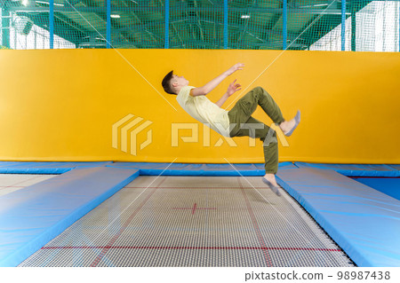 Teenage boy jumping on trampoline park in sport center Teenage boy jumping on trampoline park in sport center 98987438