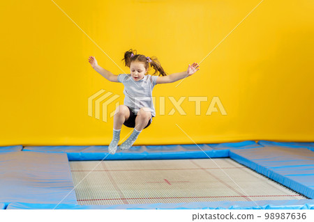 Happy little girl jumping on trampoline in fitness center 98987636