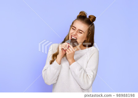 happy woman in sweater biting sweet chocolate bar 98988198