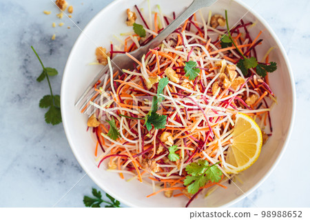 Spring carrots, beets, cabbage salad with nuts and herbs in white bowl. Spring carrots, beets, cabbage salad with nuts and herbs in white bowl. 98988652