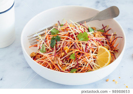 Spring carrots, beets, cabbage salad with nuts and herbs in white bowl. 98988653