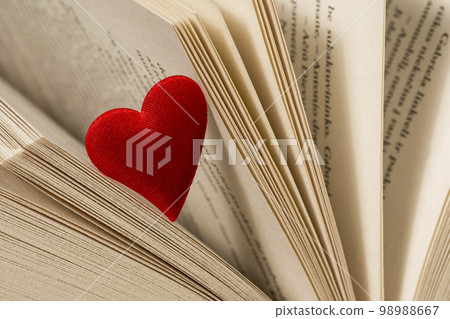 Close-up view of red heart on the open book pages Close-up view of red heart on the open book pages 98988667
