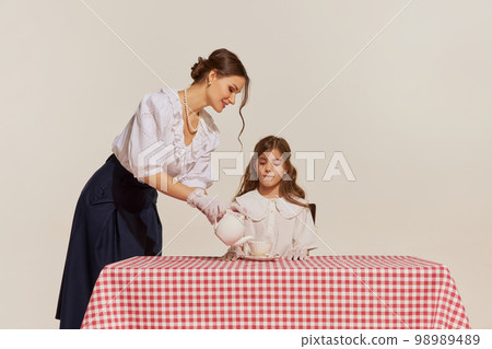 Portrait of young woman and little girl, mother and daughter isolated over light background. Concept of beauty, retro style, fashion, elegance, 60s, 70s, family. Portrait of young woman and little girl, mother and daughter isolated over light background. Concept of beauty, retro style, fashion, elegance, 60s, 70s, family. 98989489