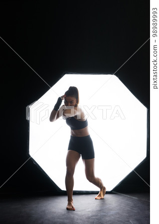 Strong sportswoman in boxing gloves prepared high kick. Isolated on white, red, yellow background 98989993