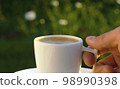 Male hand putting cup of coffee on a table 98990398