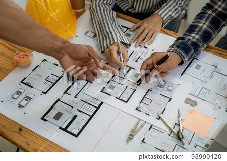 Architect and engineer team working with blueprints for architectural plan, engineer sketching a construction project, green energy concept 98990420