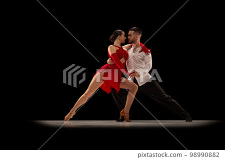 Beautiful, talented, attractive young man and woman, professional dancers performing, dancing tango over black background. Concept of art, beauty, motion 98990882