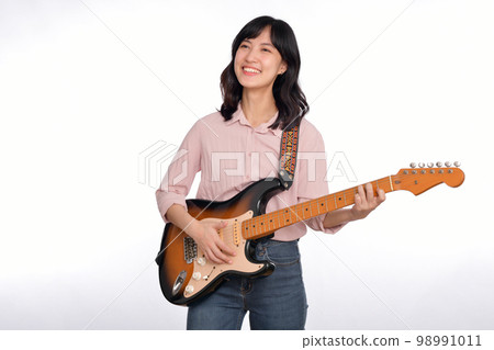 Asian woman playing a vintage sunburst electric guitar isolated on white background Asian woman playing a vintage sunburst electric guitar isolated on white background 98991011