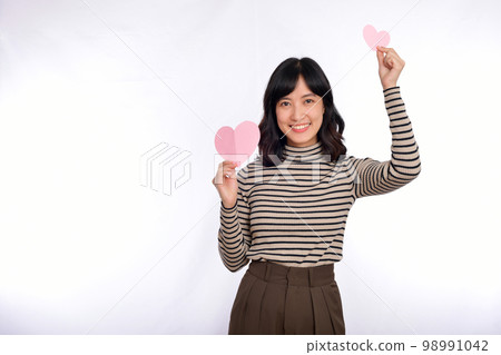 Beautiful young asian woman holding a paper heart while standing against white background. Beautiful young asian woman with paper heart. Beautiful young asian woman holding a paper heart while standing against white background. Beautiful young asian woman with paper heart. 98991042