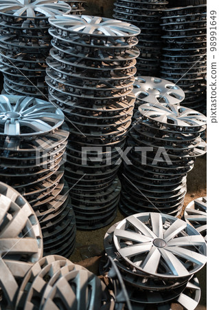 stack of various alloy wheels in tire store 98991649