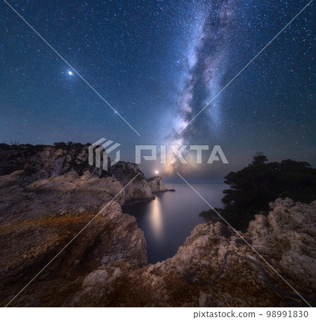 Milky Way and lighthouse on the mountain peak at starry night Milky Way and lighthouse on the mountain peak at starry night 98991830