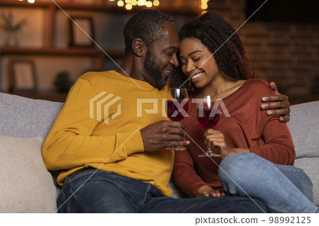 Loving black husband hugging his pretty wife, home interior Loving black husband hugging his pretty wife, home interior 98992125