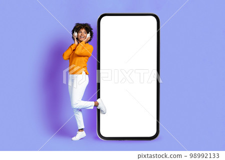 Pretty black lady listening to music in headphones, mobile app Pretty black lady listening to music in headphones, mobile app 98992133