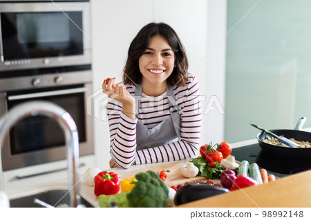Cheerful young middle eastern woman cooking at home 98992148