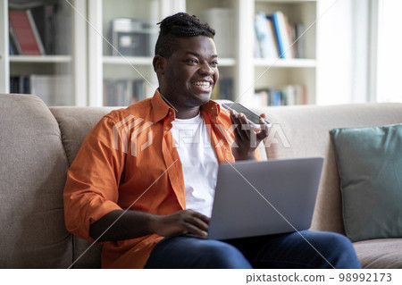 Young african american businessman working from home, sending voice mail 98992173