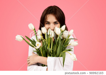 Cheerful young european lady smelling bouquet of flowers, enjoy lifestyle, aroma of tulips, rejoice spring 98992183