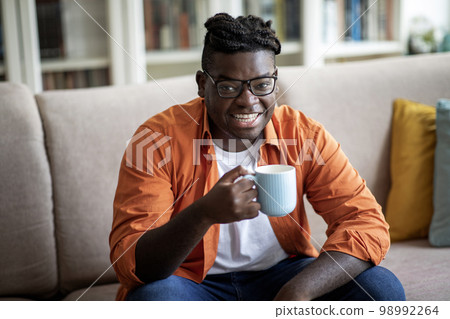 Cheerful fat african american man enjoying morning coffee at home 98992264