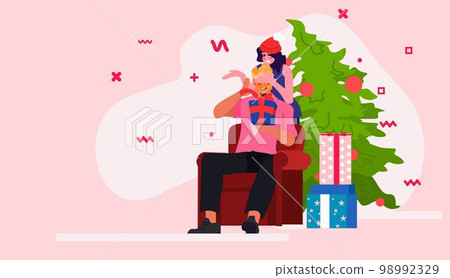 woman closing man's eyes playing guess who game near decorated fir tree happy new year merry christmas holidays celebration woman closing man's eyes playing guess who game near decorated fir tree happy new year merry christmas holidays celebration 98992329