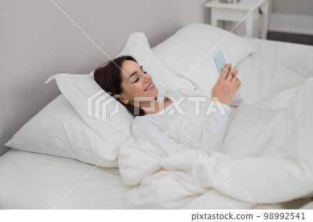 Happy pretty lady waking up with morning message from lover 98992541