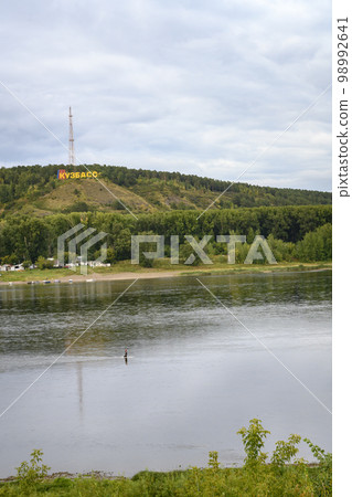 Tom River near the city of Kemerovo and fisherman crossing the river on foot Tom River near the city of Kemerovo and fisherman crossing the river on foot 98992641