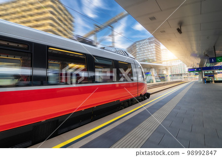 Red high speed train in motion on the railway station at sunset 98992847