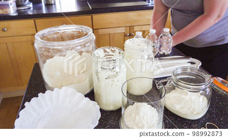 Feeding sourdough starter with water and flour. Feeding sourdough starter with water and flour. 98992873