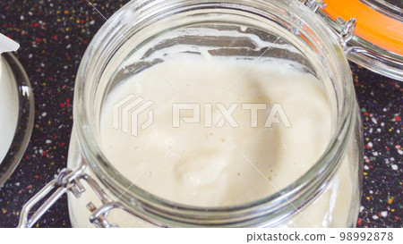 Feeding sourdough starter with water and flour. 98992878