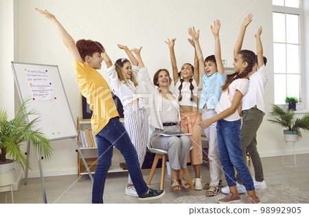 Motivated elementary school students and their teacher support each other during creative lesson. 98992905