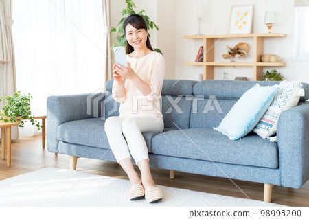 Middle woman operating a smartphone in the room 98993200