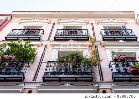 Traditional iron balcony with pots hanging from the railing 98993706