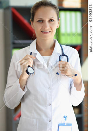 Smart female doctor holding stethoscope and looking at camera. Smart female doctor holding stethoscope and looking at camera. 98993838
