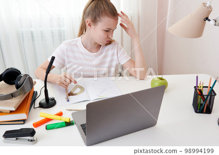 Teenage girl studying via video conference, e-learning with teacher and classmates on computer at home. Homeschooling and distance learning ,online education concept Teenage girl studying via video conference, e-learning with teacher and classmates on computer at home. Homeschooling and distance learning ,online education concept 98994199