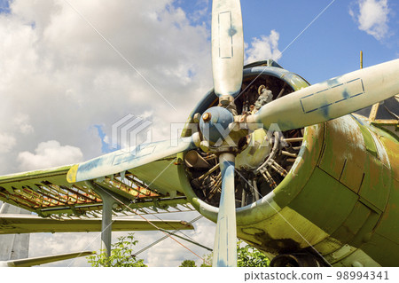A fragment of airplane wing with four-bladed aircraft propeller against blue sky A fragment of airplane wing with four-bladed aircraft propeller against blue sky 98994341