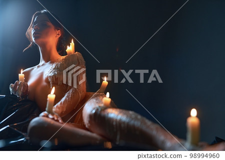 Naked woman with burning candles on body 98994960