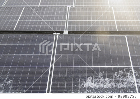 Solar panel in winter. Solar panels are covered with snow on the roof of the building, the use of modules in difficult weather conditions. Electricity production in winter, with copy space Solar panel in winter. Solar panels are covered with snow on the roof of the building, the use of modules in difficult weather conditions. Electricity production in winter, with copy space 98995755