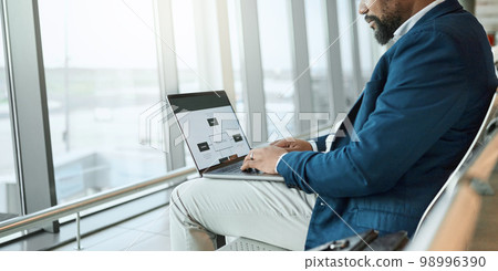 Travel, businessman and at an airport working on a laptop and waiting at terminal or boarding lounge. Entrepreneur, corporate or employee using computer at airline hub about to go on a flight Travel, businessman and at an airport working on a laptop and waiting at terminal or boarding lounge. Entrepreneur, corporate or employee using computer at airline hub about to go on a flight 98996390