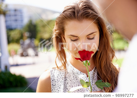 Woman, smelling rose and outdoor for valentines day date at a city park with love, romance and beauty. Face of person with red flower as gift or present to celebrate Paris couple holiday in summer 98997277