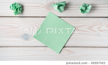 Flat lay of blank green sticker sticky note near crumpled notes on grey wooden table. Search, no idea, brainstorming. 98997403