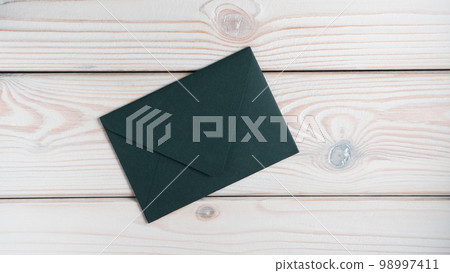 Flat lay of closed sealed green emerald envelope on grey wooden table. Correspondence, mailing, post office, stationary. Flat lay of closed sealed green emerald envelope on grey wooden table. Correspondence, mailing, post office, stationary. 98997411