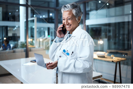 Doctor, senior woman and phone call in hospital conversation, talking and networking. Smartphone, night and female medical physician in discussion, telehealth or consulting for support in clinic. Doctor, senior woman and phone call in hospital conversation, talking and networking. Smartphone, night and female medical physician in discussion, telehealth or consulting for support in clinic. 98997478