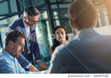 Business people, meeting and talk for strategy, planning and success with teamwork, vision and leader. Businessman, leadership and group at desk with woman, man and discussion while sitting in office Business people, meeting and talk for strategy, planning and success with teamwork, vision and leader. Businessman, leadership and group at desk with woman, man and discussion while sitting in office 98997580