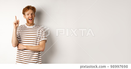 Young man with red hair having an idea, raising finger to say suggestion, standing happy over white background Young man with red hair having an idea, raising finger to say suggestion, standing happy over white background 98997698