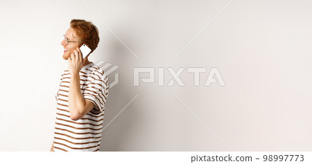 Profile of happy young handsome man talking on mobile phone, looking left and smiling, standing over white background Profile of happy young handsome man talking on mobile phone, looking left and smiling, standing over white background 98997773