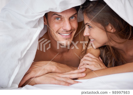 Love, portrait and couple relax in bed, waking up and bonding in a bedroom together, happy and romantic. Face, man and woman, intimate and resting at hotel for valentines day, anniversary or bond 98997983